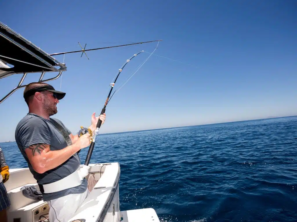 Pescaria em alto mar: tudo o que você precisa saber 2 Pescaria em alto mar com barco equipado e varas de pesca em ação no oceano azul.